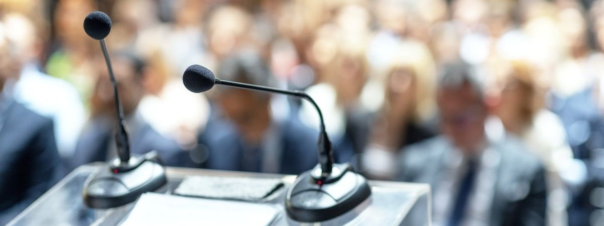 two microphones blurred audience shutterstock_2604940459
